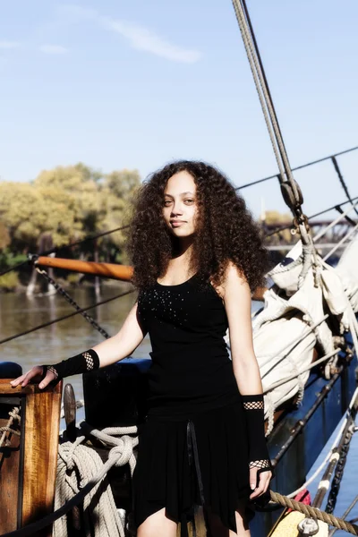 Jovem mulher vestido preto de pé no navio de vela arco — Fotografia de Stock