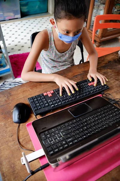 Covid 19流感大流行期间 东南亚女中学生在家中使用笔记本电脑在线学习 戴口罩 — 图库照片
