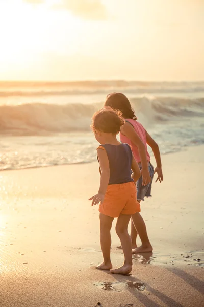 Twee kleine meisjes verkennen het strand bij zonsondergang — Stockfoto