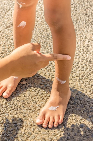 Αντιηλιακό γαλάκτωμα στα πόδια του παιδιού — Φωτογραφία Αρχείου