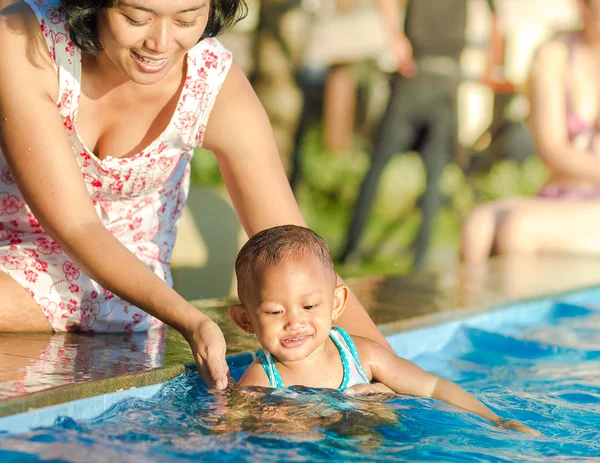 Madre animar a los niños pequeños a divertirse en la piscina — Foto de Stock