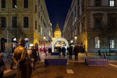 Budapeşte Macaristan - 14 Aralık 2019: Turistler Macaristan 'ın Budapeşte kentindeki Aziz Steven Bazilikası' nda Noel ışıklarının keyfini çıkarıyorlar. Geleneksel Noel fuarı her yıl yaklaşık 900.000 ziyaretçiyi çekiyor..