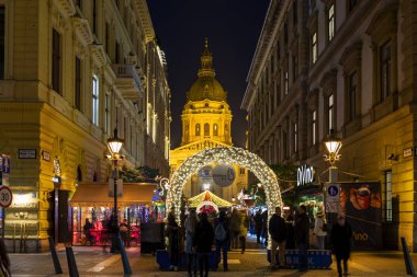 Budapeşte Macaristan - 14 Aralık 2019: Turistler Macaristan 'ın Budapeşte kentindeki Aziz Steven Bazilikası' nda Noel ışıklarının keyfini çıkarıyorlar. Geleneksel Noel fuarı her yıl yaklaşık 900.000 ziyaretçiyi çekiyor..
