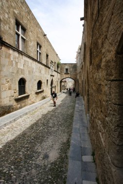 Güneşli bir günde eski caddede yürüyen insanların manzarası 