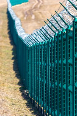 Sınır koruması için üstte dikenli tel olan çit.