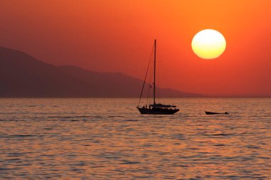 Doğanın arka planında gün batımına doğru yelken açmak.