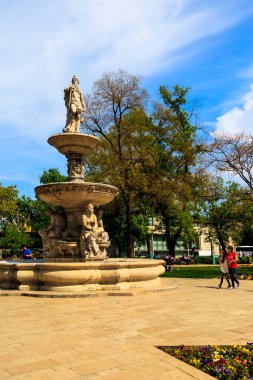 Güneşli bir günde parkta heykelleri olan güzel bir çeşme. 