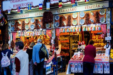 Şehirdeki pazarda tezgahların yanında yürüyen turistler  