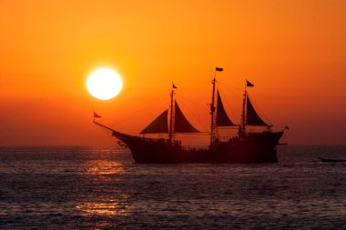 Doğanın arka planında gün batımına doğru yelken açmak.