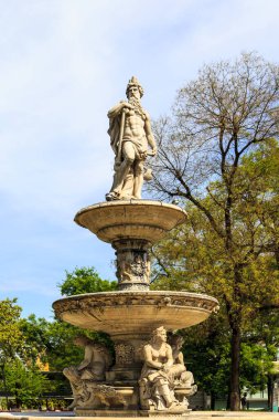 Güneşli bir günde parkta heykelleri olan güzel bir çeşme. 