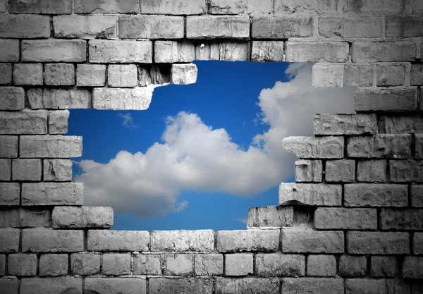 Hole in brick wall revealing clouds — Stock Photo, Image