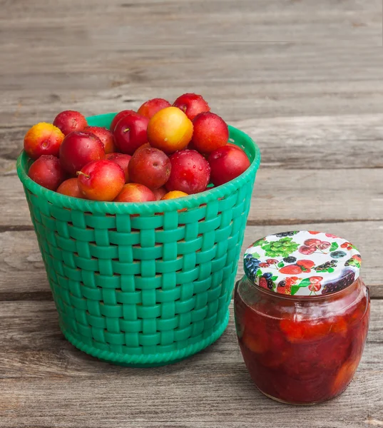 Jar of jam and basket with plums — Stock Photo, Image