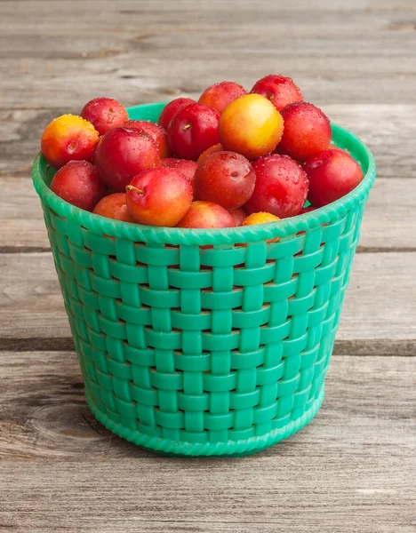 Green basket with red plums — Stock Photo, Image