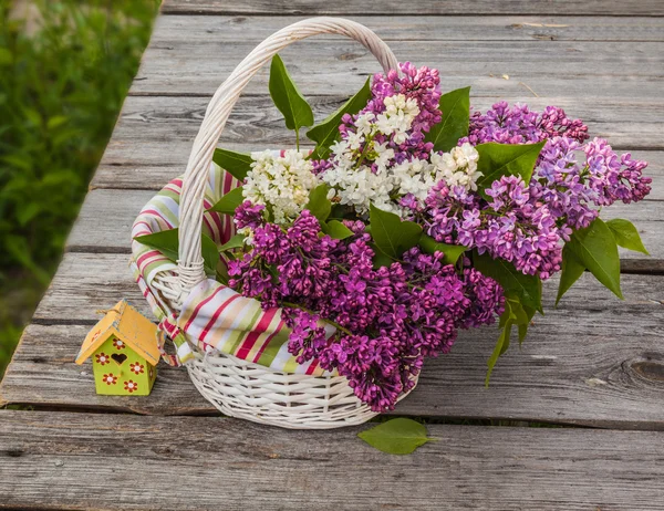 Basket with a branch of lilac — Stock Photo, Image