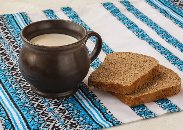 Mug of milk and a slice of rye bread — Stock Photo, Image