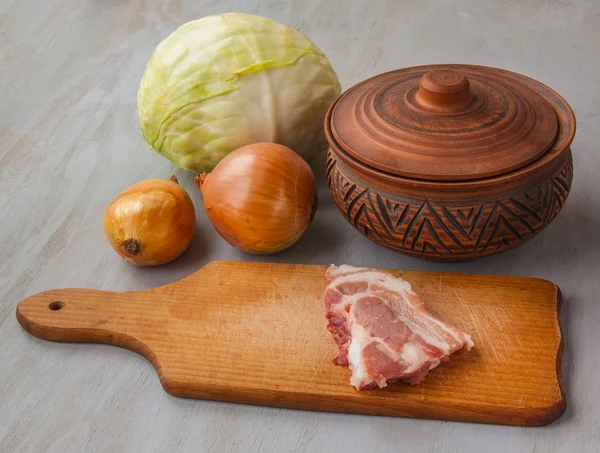 Porc cru sur une planche à découper et pot — Photo