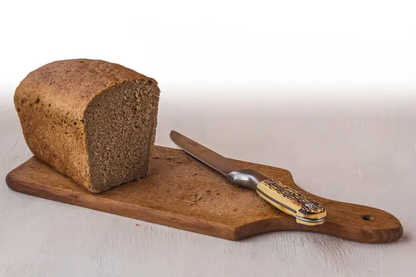 Brot und Messer auf einem Brett — Stockfoto