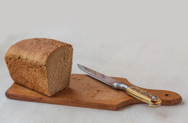 Brot und Messer auf einem Brett — Stockfoto