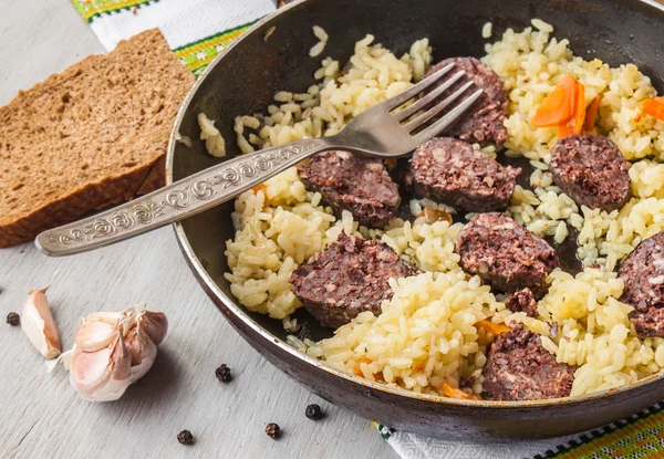 Pilaf in a pan and black pudding — Stock Photo, Image