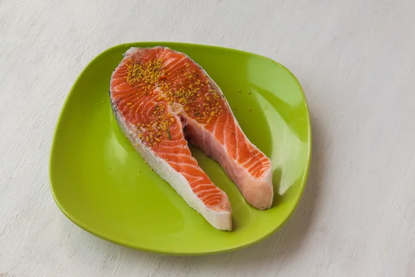 Pedaço de peixe vermelho num prato verde — Fotografia de Stock
