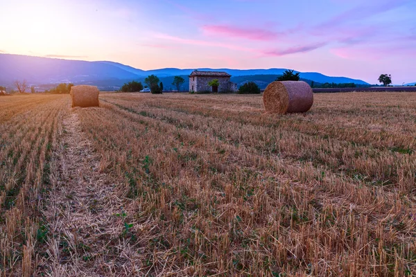 Puesta de sol sobre campo de granja con fardos de heno cerca de Sault — Foto de Stock