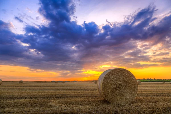 Zonsondergang over landelijke weg en hooi balen — Stockfoto