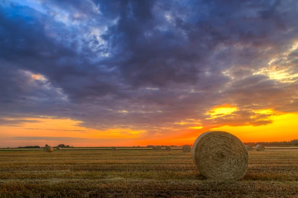 Puesta de sol sobre caminos rurales y fardos de heno —  Fotos de Stock