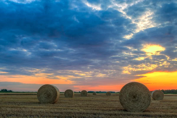 Закат над сельской дорогой и тюками сена — стоковое фото