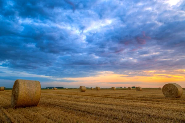 Sunset over rural road and hay bales — Stock Photo, Image