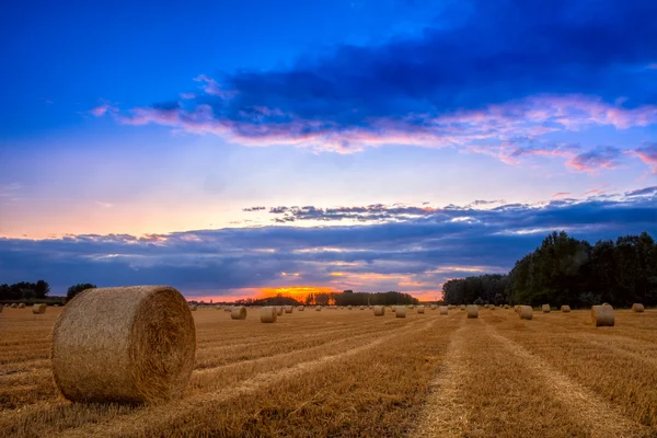 Einde van dag over veld met Baal hooi — Stockfoto