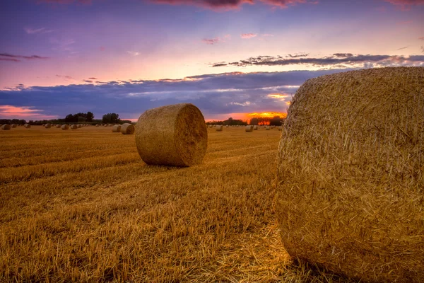 Einde van dag over veld met Baal hooi — Stockfoto