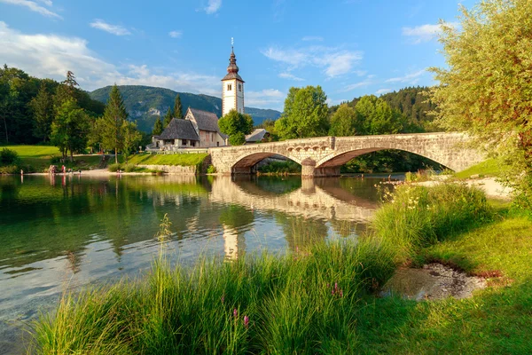 Iglesia de Sv. Juan el Bautista y un puente junto al lago Bohinj — Foto de Stock