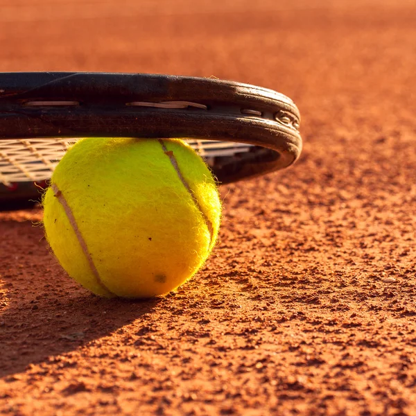 Pelota de tenis y raqueta en una pista de tenis de arcilla — Foto de Stock