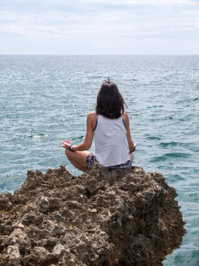 Güneş doğarken kumsalda yoga yapan güzel bir kadın.