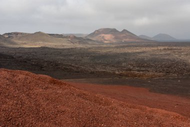 Ufukta dağlar olan volkanik bir manzara.