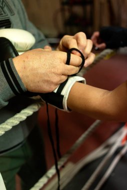 Erkek koç, kadına boks eldivenini ele bağlamada yardım eder.