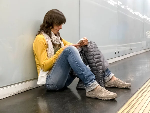 Mujer Joven Sentada Suelo Usando Teléfono Mientras Apoya Pared Plataforma — Foto de Stock