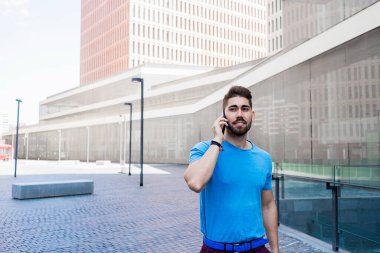 Neşeli modern iş adamı telefonda konuşuyor ve dışarıda yürürken gülümsüyor.