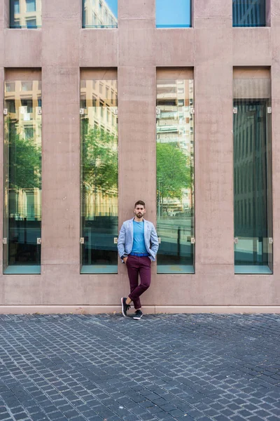 オフィスビルの壁にもたれている間 カジュアルな服を着て都市の背景に若い髭の男 ファッションのモデル — ストック写真