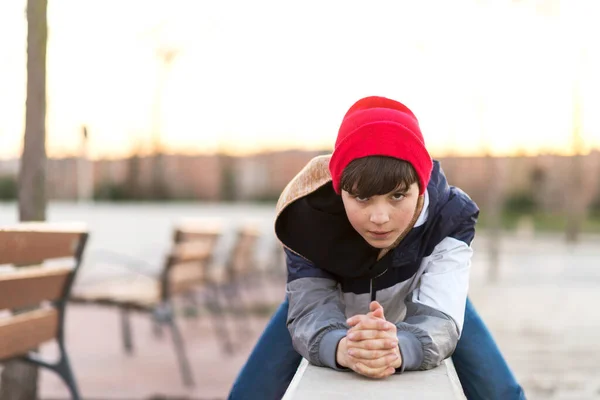 一个时髦的青少年坐在城市公园的栅栏上 — 图库照片
