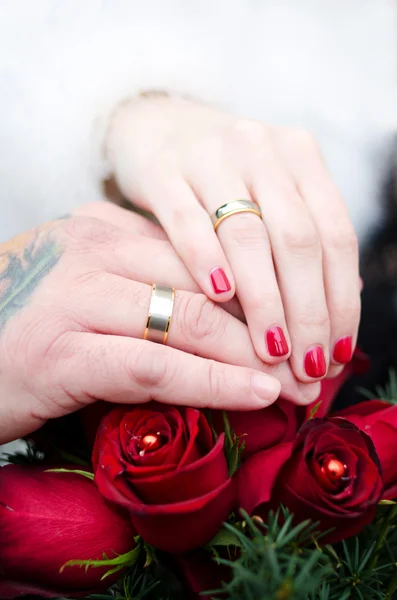 Mãos e anéis no buquê de casamento — Fotografia de Stock
