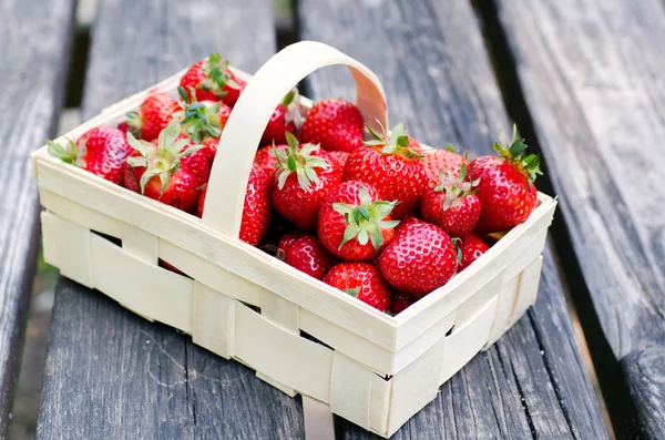 Ripe strawberries in wooden box over wooden table — Stock Photo, Image