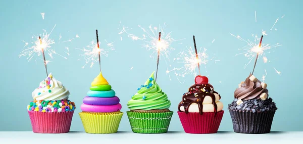 誕生日パーティーのために輝きで飾られた明るい色のお祝いカップケーキの盛り合わせ — ストック写真