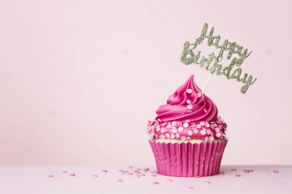 Birthday background with celebration cupcake with happy birthday banner on a pink background