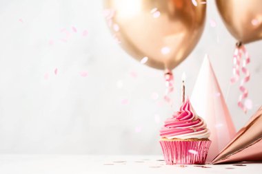Pembe doğum günü pastası, parti şapkaları ve gül sarısı balonlarla doğum günü kutlaması.