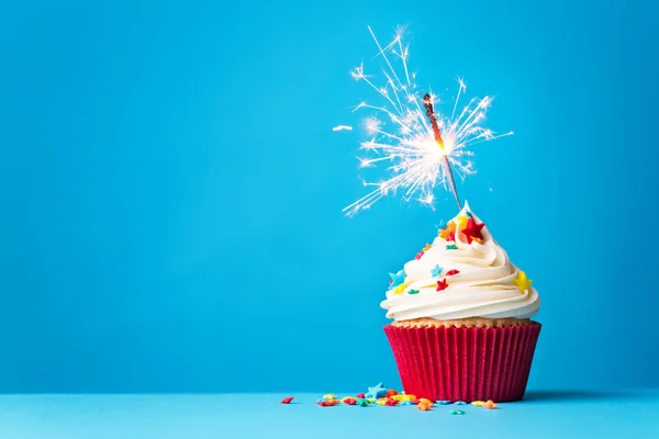 Cupcake with sparkler on blue — Stock Photo, Image