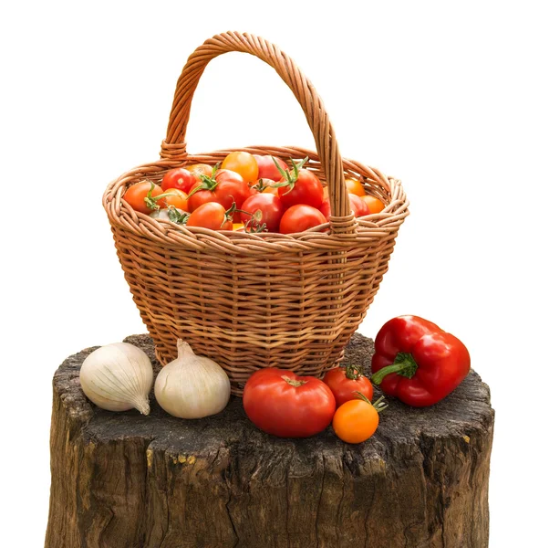 Tomatoes in basket, onion and pepper on stump in garden — Stock Photo, Image