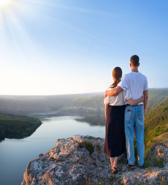 2 genç taşralı erkek, neşe dolu bir eğlence istirahatı için güneşli bir ortama bakıyor. Mutlu gülümseme bayan yürüyüşçü el ele tutuşun barış okyanus yürüyüşü kaya tepesi sahnesine tırmanın