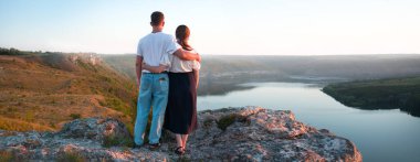 2 genç taşralı erkek, neşe dolu bir eğlence istirahatı için güneşli bir ortama bakıyor. Mutlu gülümseme bayan yürüyüşçü el ele tutuşun barış okyanus yürüyüşü kaya tepesi sahnesine tırmanın