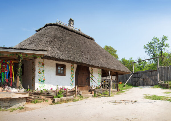 Hortica, Zaporizhia, 2015 JUNE. Zaporizhian National Sich Cossack Museum. Typical aged peasant white homestead, wooden paling and well-crane in yard. Panoramic view with space for text on blue sky